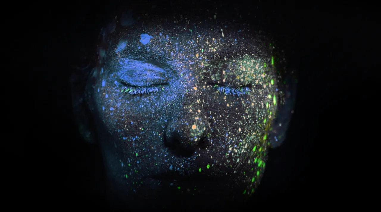Close-up of eyelashes flecked with glowing paint